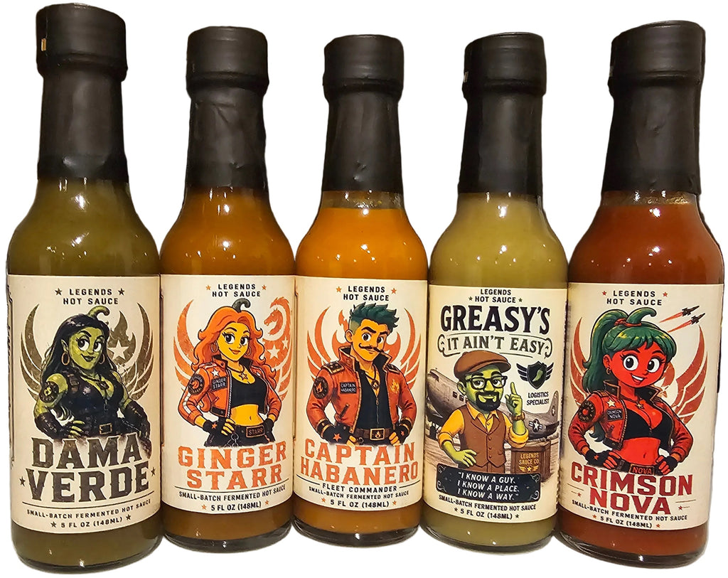 Five bottles of hot sauce with colorful labels on a kitchen counter.